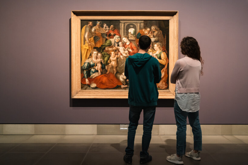 Een man en een vrouw kijken naar een schilderij. Het renaissancewerk toont een religieus tafereel. Op het werk uit de zestiende eeuw staat de familie van de heilige Anna afgebeeld.